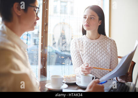Porträt von zwei junge Unternehmerinnen bei Treffen im Café: eine Dokumentation zeigt und erklärt, er und die anderen lauschte Stockfoto