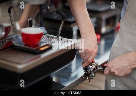 Händen der Barista beim Mahlen der Kaffeebohnen Stockfoto