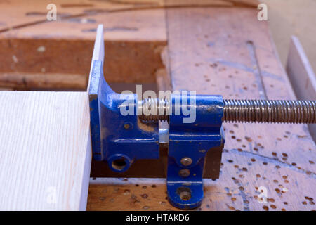 Metallklemme zusammenzuhalten zwei Stücke Holz, die geklebt worden in Tischler Werkstatt Stockfoto