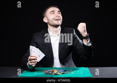 Mann mit vier Asse in die Hände spielen auf Tisch im Casino auf schwarzem Hintergrund Stockfoto