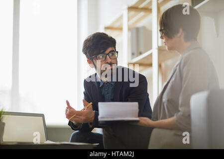 Moderne orientalische Mann trägt kreative Frisur und Brille lauschte seinem Kollegen während der Diskussion über Geschäftsideen im modernen Büro Stockfoto