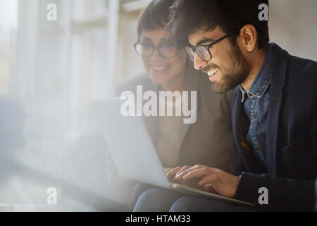 Porträt von zwei erfolgreiche Unternehmer Prüfung Statistikinformationen, beide Lächeln mit Freude beim Betrachten der Laptop-Bildschirm Stockfoto