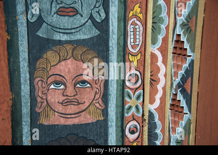 Bhutan Thimphu. Chong Gia ca Tempel. Detail der kunstvoll bemalten Gesichtern um hölzerne Tempeltür. Stockfoto