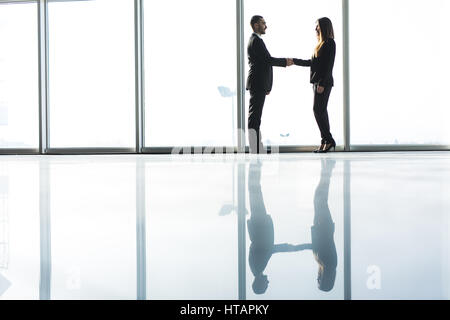 Junges Unternehmen Partner Handshake nach Vereinbarung gegen große Panoramafenster machen. Stockfoto