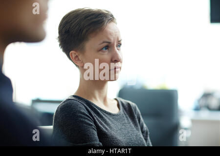 Seite Ansicht Porträt des jungen blasse Frau mit Kurzhaarschnitt, Seminar in Gruppe suchen besorgt und traurig anhören Stockfoto
