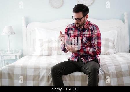 Gut aussehender Mann putzt sich für die Arbeit am Morgen im Schlafzimmer Stockfoto