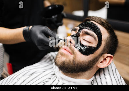 Entspannter Mann mit Maske auf Gesicht zu reinigen Stockfoto