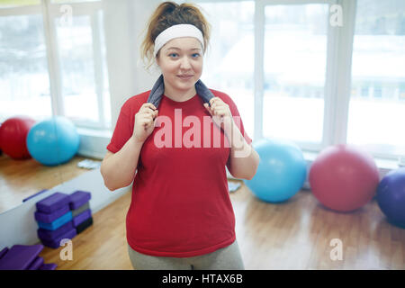 Porträt, glücklich niedlich übergewichtige Frau mit Handtuch nach dem Training im Fitness-Studio und lächelnd zu Kamera Stockfoto