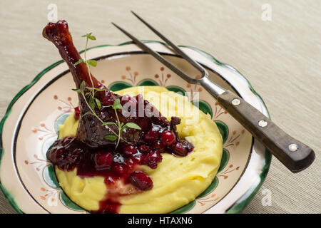 Gebratene Entenkeule mit gestampften Kartoffeln, Äpfel und rote Johannisbeeren in Rotweinsauce Stockfoto