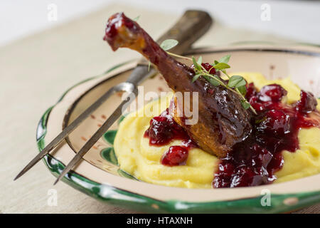 Gebratene Entenkeule mit gestampften Kartoffeln, Äpfel und rote Johannisbeeren in Rotweinsauce Stockfoto