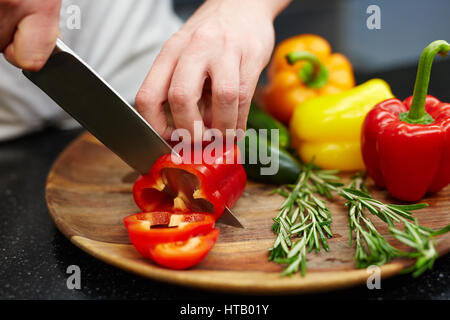 Koch schneiden Paprika auf Holzbrett Stockfoto