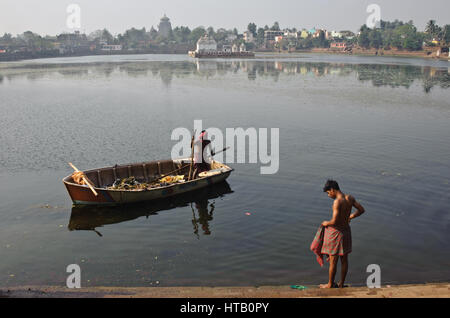 Reinigung der See "Bindu Sagar" + junge Mann bereit, Baden im See (Indien) im Hintergrund, ist der Lingaraj Tempel sichtbar. Stockfoto