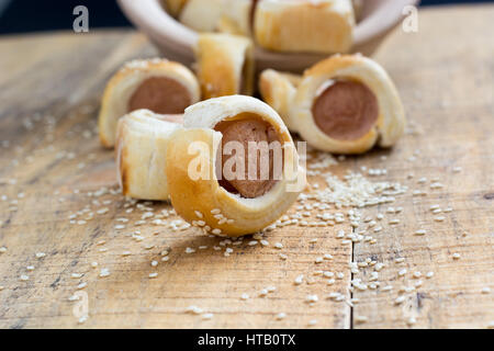 Hausgemachte Schweine in eine Decke. Würstchen in Croissant Teig gebacken Kühlung auf Metallgestell mit Sesam gerollt. Selektiven Fokus Stockfoto