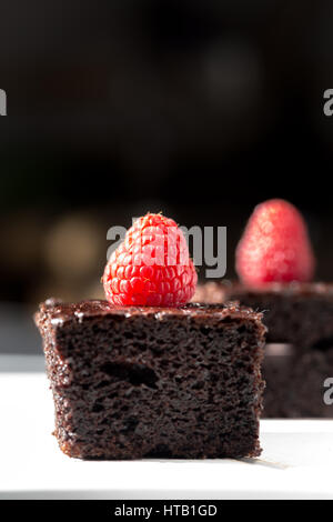 Stücke von dunkler Schokoladenkuchen mit Himbeeren dekoriert Stockfoto