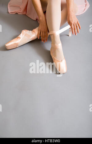 Ballett-Tänzerin am Boden sitzen und ihre Schnürsenkel zu binden. Stockfoto