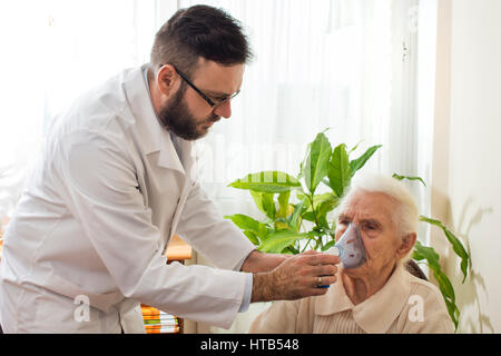 Die Arztpraxis durchgeführt einatmen. Der Arzt hält Inhalator das Gesicht einer alten Frau. Inhalation der oberen Atemwege. Stockfoto