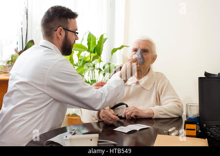Die Arztpraxis durchgeführt einatmen. Der Arzt hält Inhalator das Gesicht einer alten Frau. Inhalation der oberen Atemwege. Stockfoto