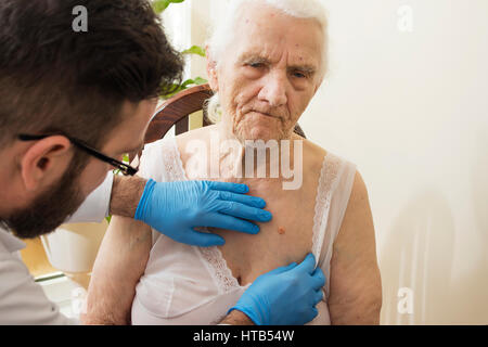 Arzt untersucht Veränderungen in der Haut einer alten Frau. Stockfoto