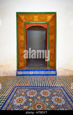 Berber Arabesken bemalte Holztür Surround und Zellige Fliesenboden. Die Petite Gericht, Bahia-Palast, Marrakesch, Marokko Stockfoto