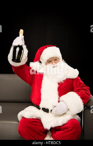 Santa Claus Holding Flasche Champagner auf schwarzem Hintergrund Stockfoto