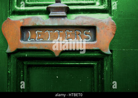 Ein Kupfer-Buchstaben-Slot an einer grünen Tür. Stockfoto