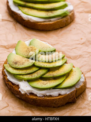 frische Rohe geschnittene Avocado Sandwich auf braunem Papier Stockfoto