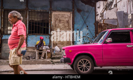 Havanna, Kuba am 23. Dezember 2015: ein Mann geht auf eine Straße in Centro Habana mit seinem Hemd Farbe von rosa Oldtimer Stockfoto