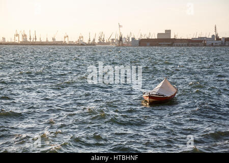 Angelboot/Fischerboot in einem Meer in Thessaloniki, Griechenland. Industrielle Seehafen ist auf einen Horizont sichtbar Stockfoto