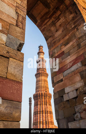 Eiserne Säule von Delhi gesehen mit Qutub Minar durch einen gemauerten Torbogen, Qitb Komplex, Delhi, Indien. Stockfoto
