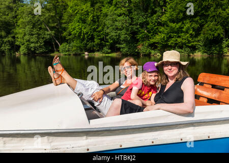 Zwei Frauen und ein Mädchen auf einem Tretboot auf ein ruhiger Fluss, umgeben von dichten Wäldern an einem sonnigen Tag; Steinbrucker Teig, Hessen, Deutschland Stockfoto