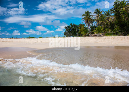 Eine Welle Spritzwasser auf den weißen Sandstrand und dem Dschungel im Hintergrund auf der unbewohnten Insel Cayo Zapatilla in Bocas del Toro; Panama Stockfoto