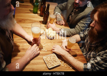 Gesellschaft der Freunde von Holztisch sitzen und reden von Glas Bier Stockfoto