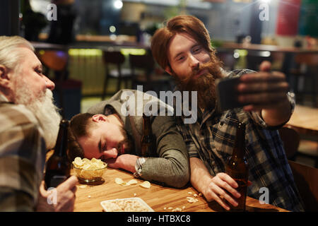 Junger Mann mit Flasche Bier machen Selfie im pub Stockfoto