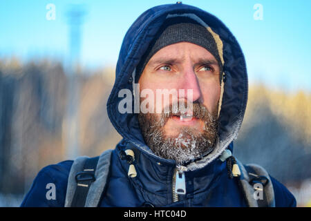 Close up Portrait des jungen Mannes mit gefrorenen vereisten Haare auf Kopf- und Barthaar Stockfoto