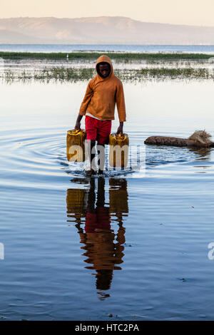 Ein Teenager sammelt Wasser aus dem See In Containern, See Awassa, Äthiopien Stockfoto