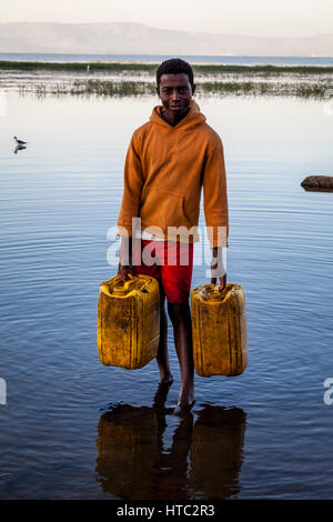 Ein Teenager sammelt Wasser aus dem See In Containern, See Awassa, Äthiopien Stockfoto