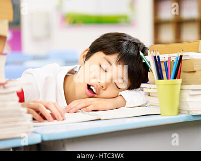 müde und erschöpft asiatischen Grundschule Schüler beim Einschlafen während des Studiums Stockfoto