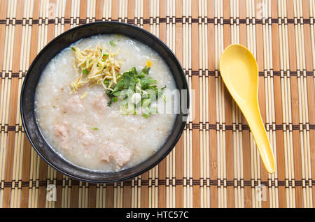 Congee Reisbrei, Reis Brei, Reissuppe auf hölzernen Hintergrund, Ansicht von oben. Stockfoto