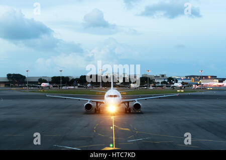 Weiße Passagierflugzeug startet von der Landebahn des Flughafens. Flugzeug bewegt sich vor dem Hintergrund der Nacht. Flugzeug-Vorderansicht. Stockfoto