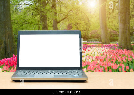 Laptop mit leeren Bildschirm auf Tisch mit blur grünen Natur im Hintergrund. Technologie-Konzept. Stockfoto