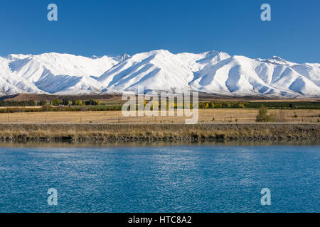 Twizel, Canterbury, Neuseeland. Blick über den Kanal Pukaki zu den schneebedeckten Gipfeln des Bereichs Ben Ohau Herbst. Stockfoto