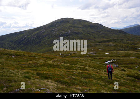 Eine einsame männliche Hillwalker auf dem Grat zwischen der schottischen Berge Corbet des Meall Na h-Eilde und Geal Charn in den schottischen Highlands. Stockfoto