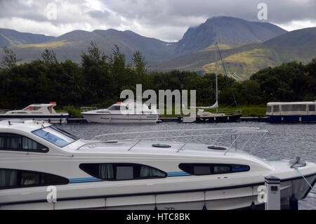 Sportboote und der Munros Anoach Mor, Carn Mor Dearg & Ben Nevis aus den Caladonian Canal in der Nähe von Fort William in den schottischen Highlands. Stockfoto