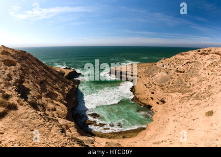 Bunte Küste mit Blick auf eine kleine Bucht mit ein paar Fischen Lodges im Souss-Massa-Nationalpark am Atlantik in Morooco, Afrika. Stockfoto