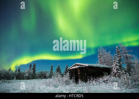 Eine verlassene Hütte über den Richardson Highway sitzt ruhig in den Schnee unter die Aurora in einer kalten Winternacht; Alaska, Vereinigte Staaten von Amerika Stockfoto