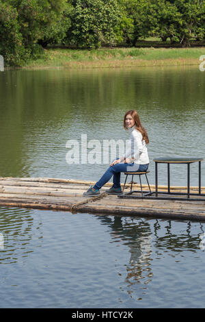 Frau sitzt auf einem Bambusfloß im Fluss Stockfoto