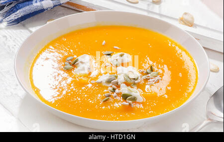Kürbissuppe mit Sahne und Kürbis Samen auf weißem Holz Hintergrund Stockfoto