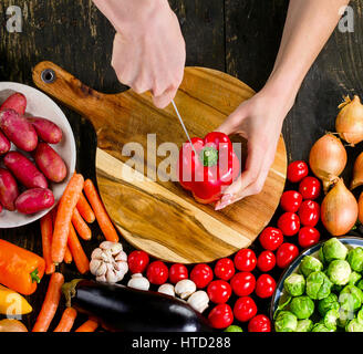 Frau die Hände schneiden von Gemüse auf Holzbrett. Gesunde Ernährung und vegetarische Konzept. Ansicht von oben Stockfoto