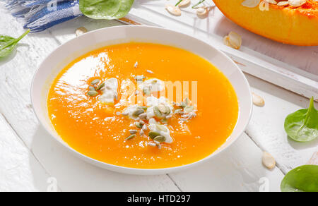 Kürbis und Karotten-Suppe mit Sahne und Kürbis Samen auf weißem Holz Hintergrund Stockfoto