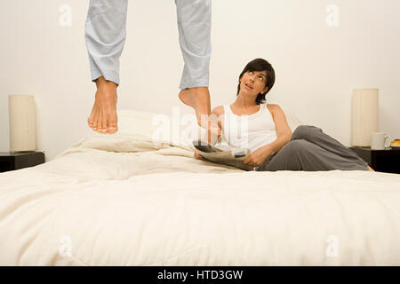 Frau ansehen Mann springen auf Bett Stockfoto